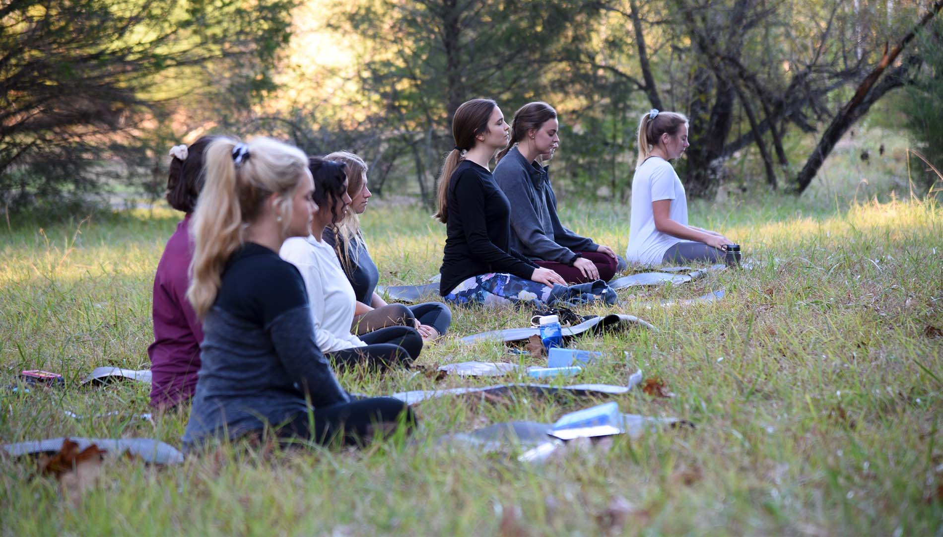 collection of female students meditating outdoors