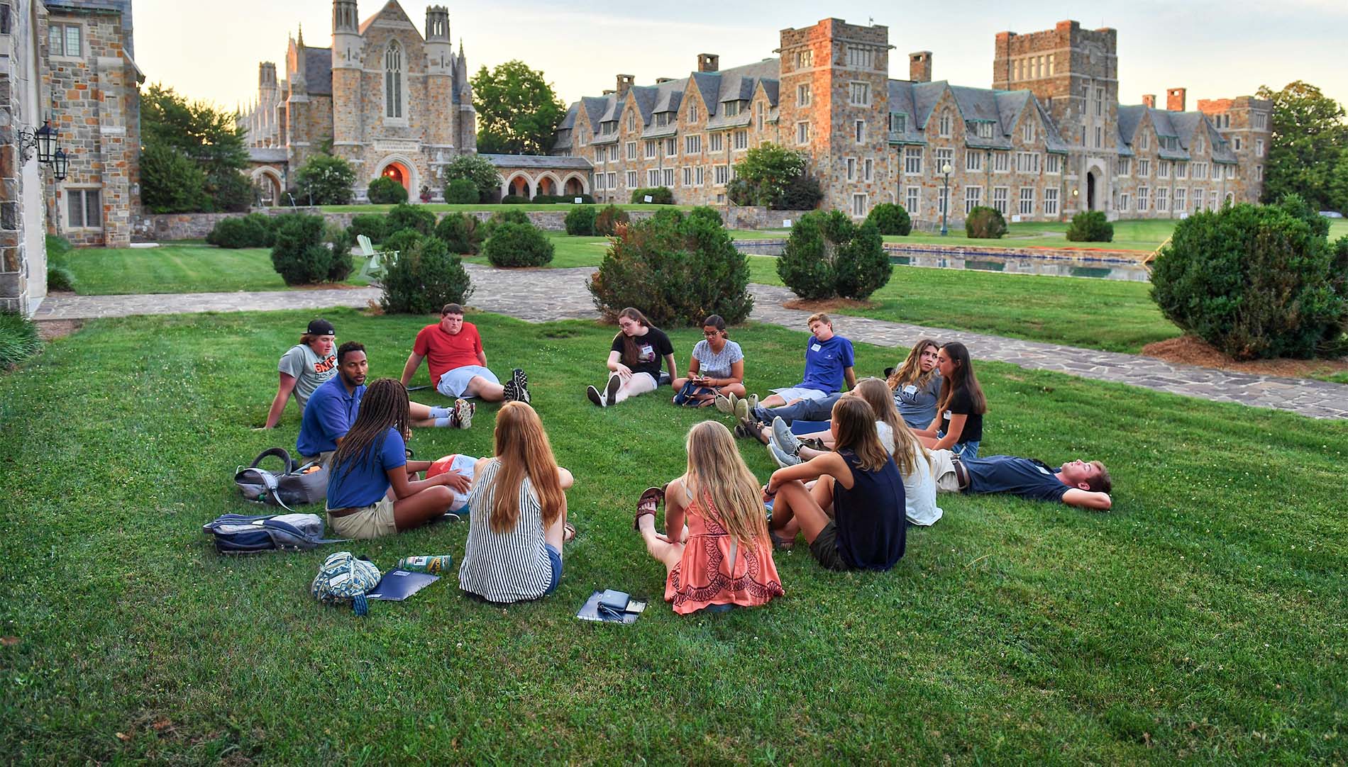 several students sitting on the lawn in a circle