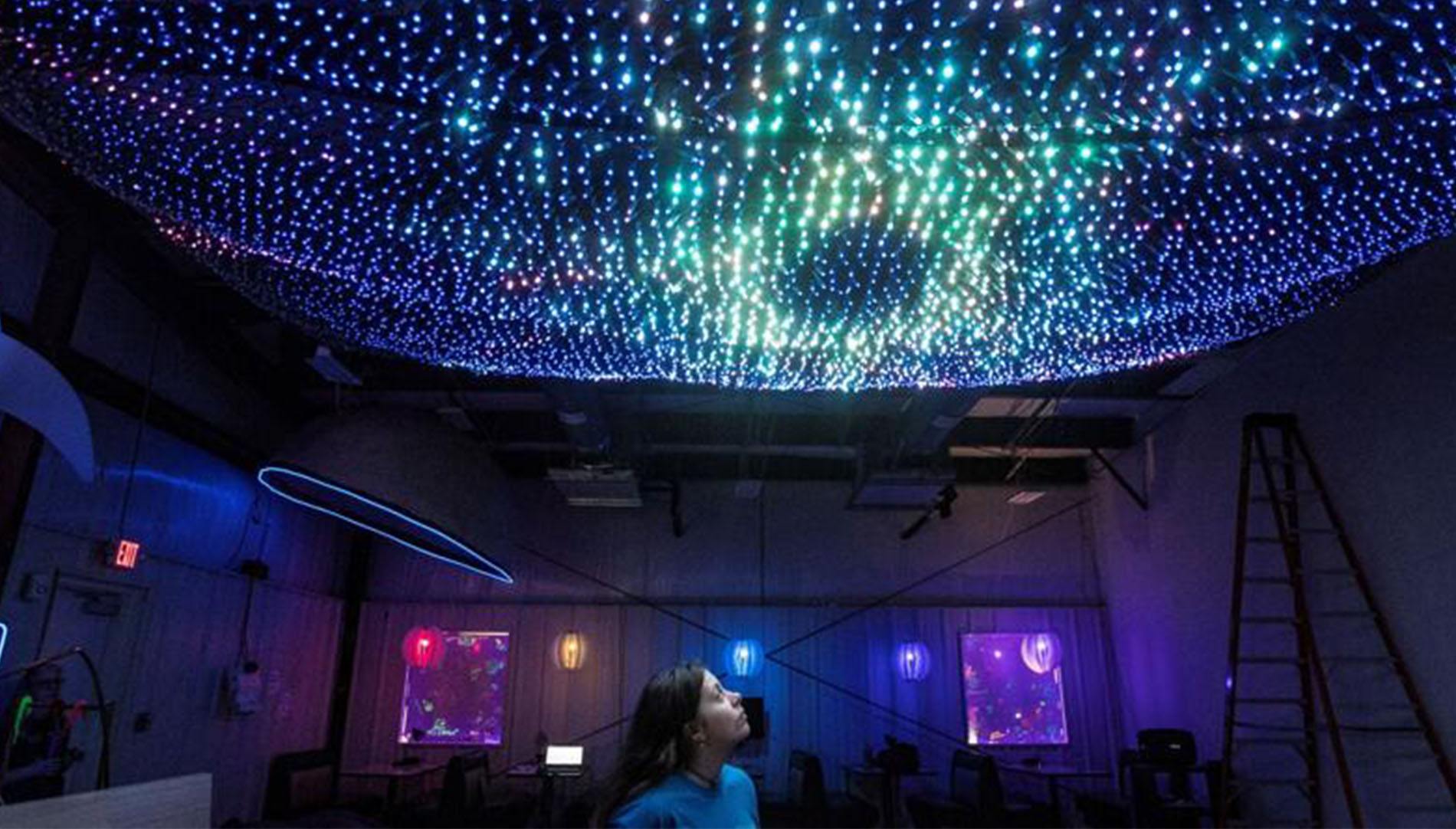 young female student looking at LED lights in the ceiling