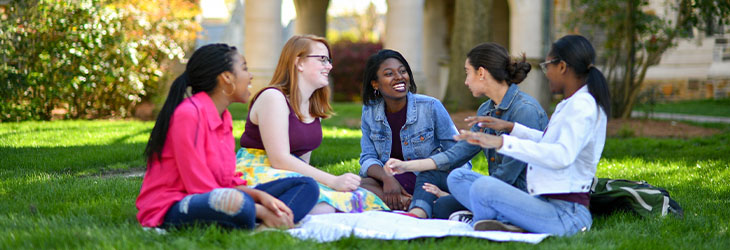 group of girls sitting on a lawn laughing